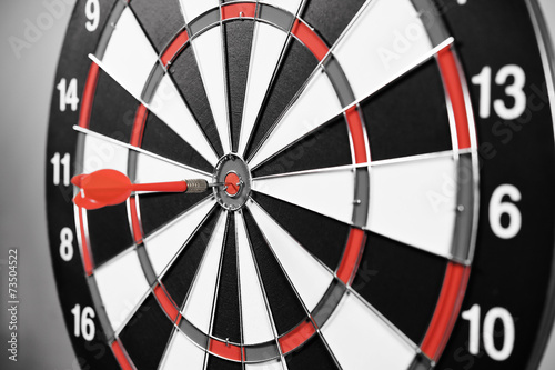 Dartboard with red darts on gray background.