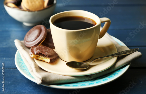 Cup of coffee with tasty cookies on color wooden background
