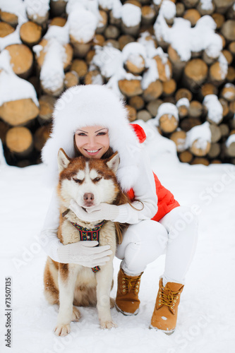 Fototapeta Naklejka Na Ścianę i Meble -  Beautiful girl with a Siberian husky in the snow.