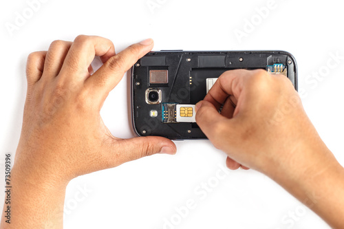 Hand holding sim card and put into smartphone isolated on white