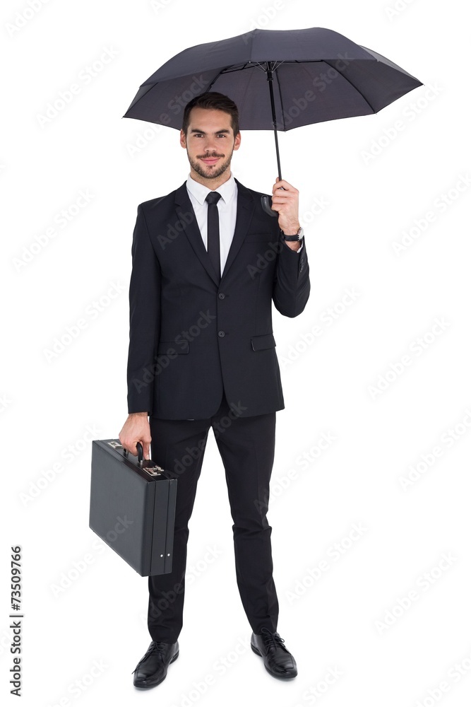 Smiling businessman under umbrella while holding briefcase Smiling businessman under umbrella while holding briefcase