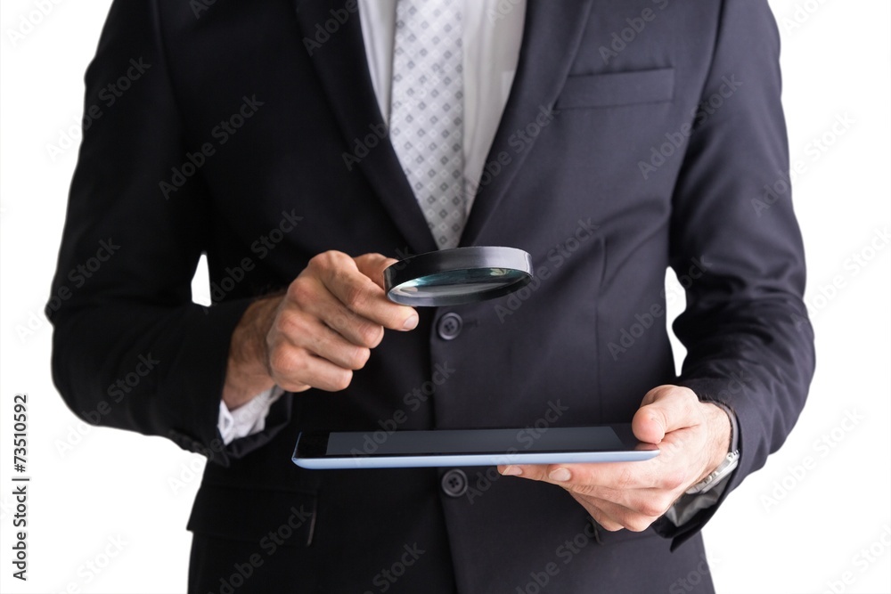 Businessman using magnifying glass and tablet Businessman using magnifying glass and tablet
