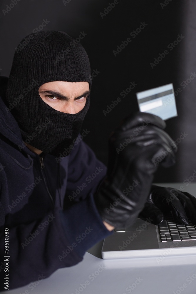 Angry hacker using credit card and laptop Angry hacker using credit card and laptop