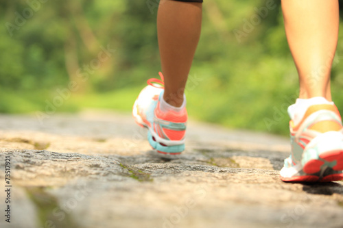 young fitness woman hiker legs walking on forest trail 