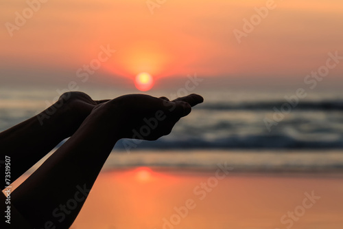 Silhouette of hands play with the sun at neach in sunset time © SKT Studio