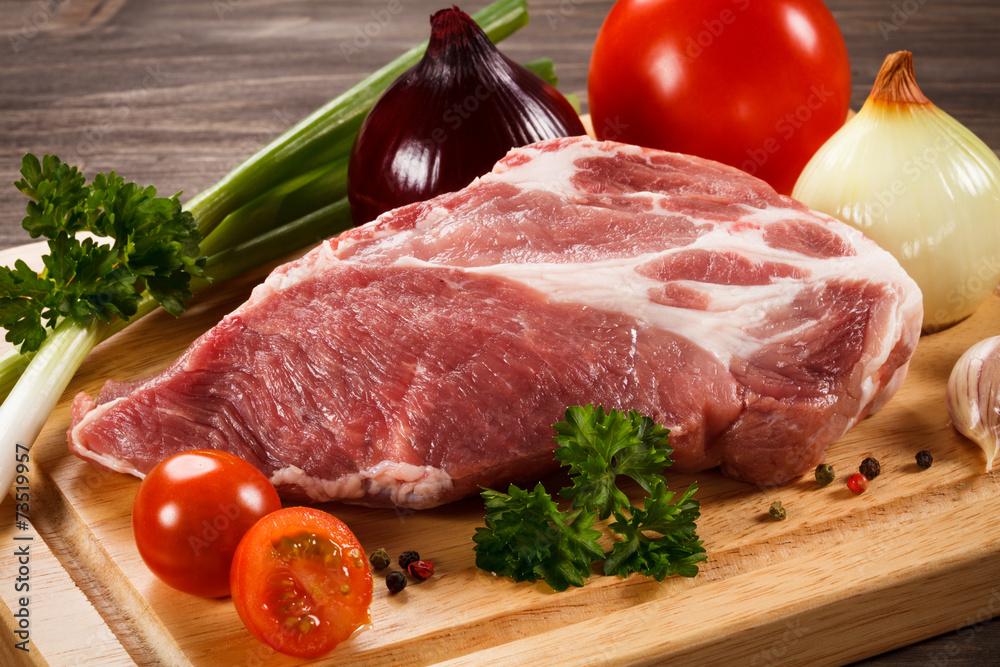 Raw pork on cutting board and vegetables Raw pork on cutting board and vegetables