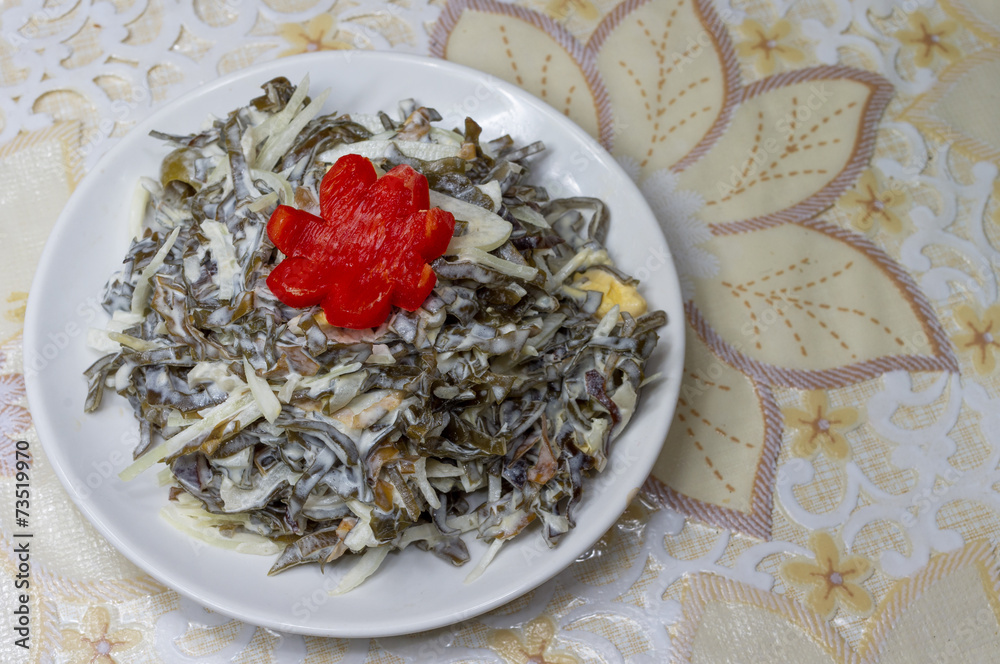 Decorated seaweed salad with egg and onion on kitchen table