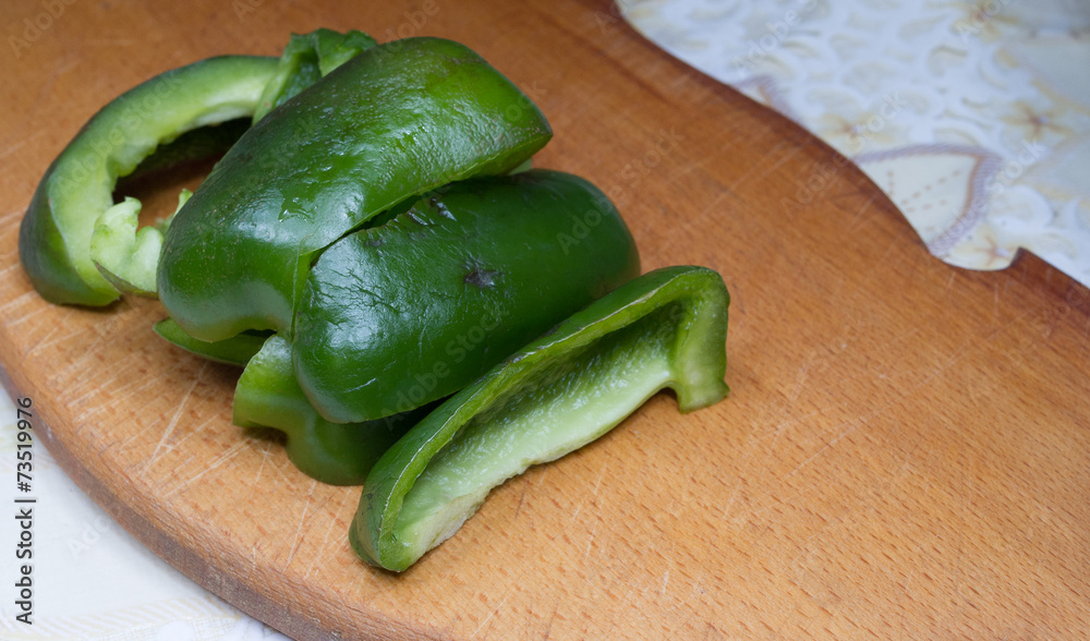 Green sliced pepper on wooden board on the table