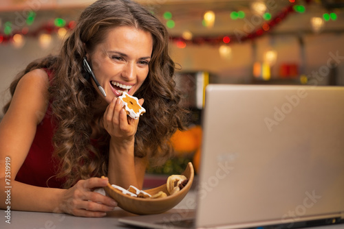 Happy young woman with christmas cookies having video chat
