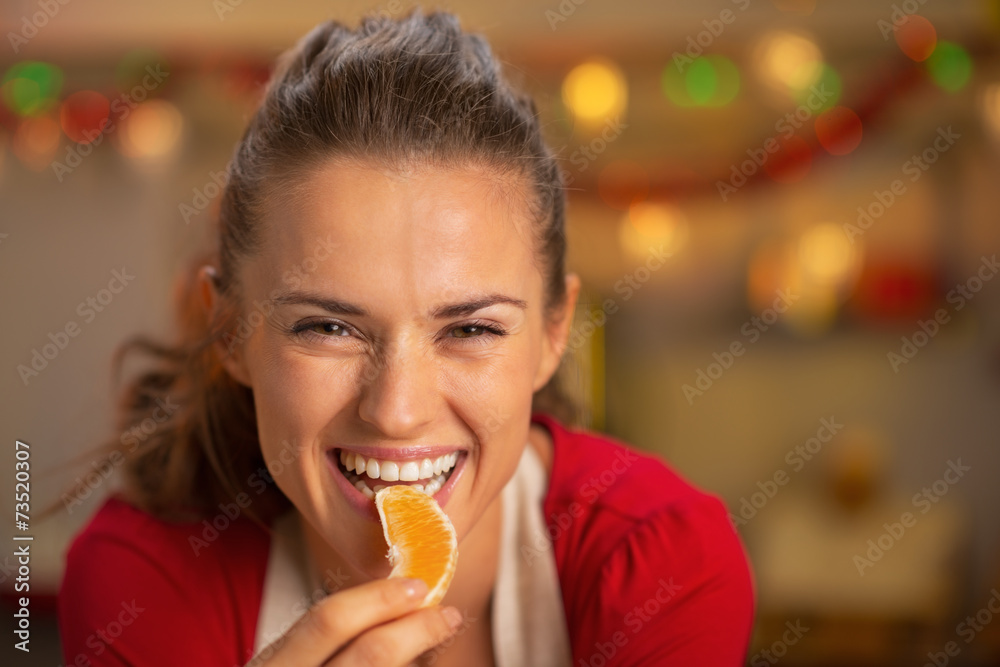 Portrait of young housewife eating orange in kitchen Portrait of young housewife eating orange in kitchen