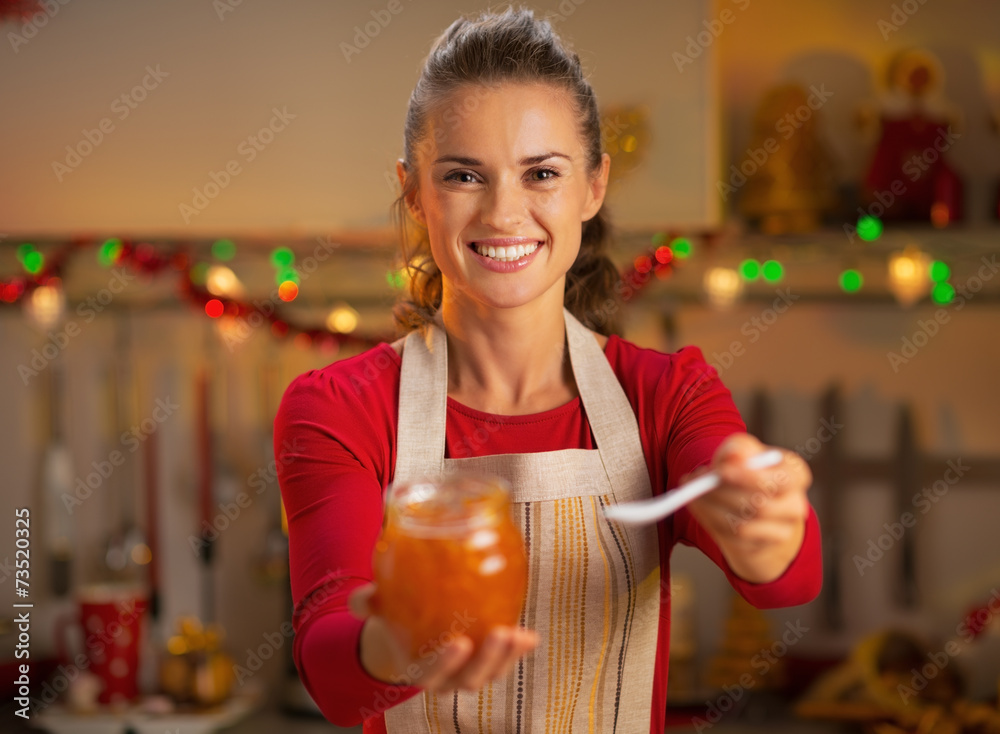Happy young housewife giving homemade orange jam Happy young housewife giving homemade orange jam