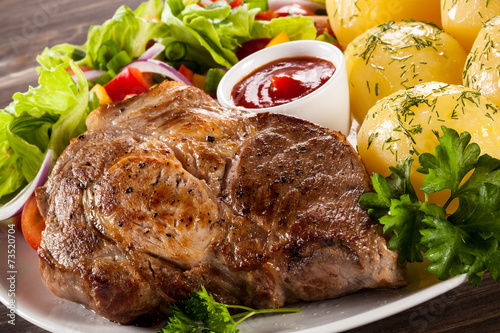 Barbecued steak, boiled potatoes and vegetable salad