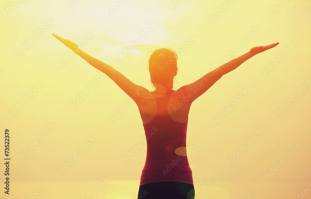 Obraz premium cheering woman hiker open arms at sunrise seaside