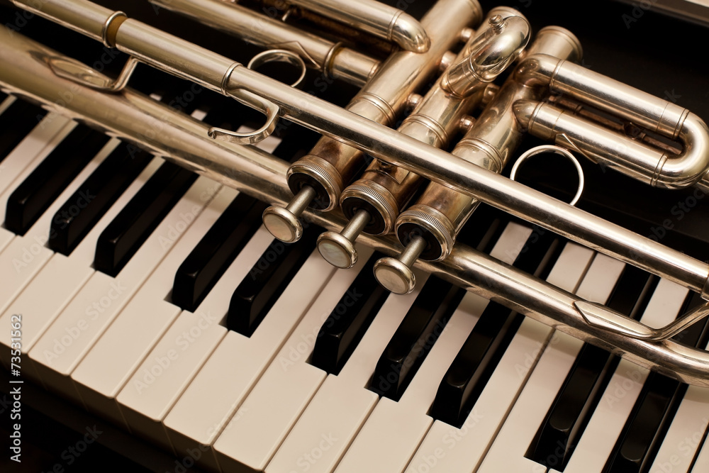 Fototapeta premium Detail of trumpet lying on the piano keys