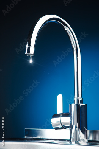mixer tap with water drop, blue background