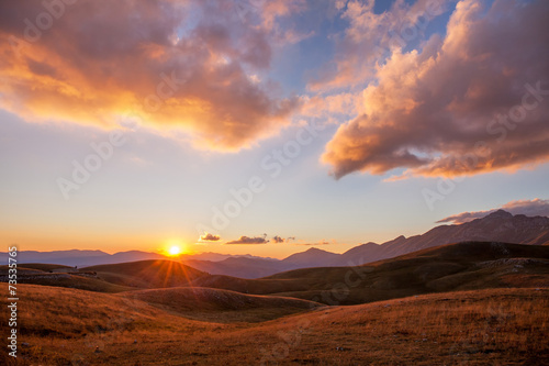 Tramonto tra le montagne e nuvole tinte di rosa