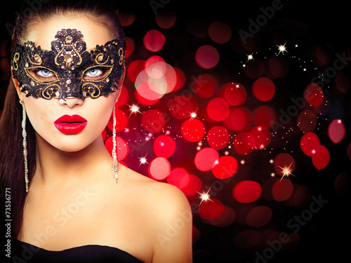 Woman wearing carnival mask over glowing red background