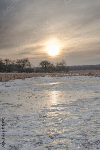 Sunrise over a frozen meadow in early spring.