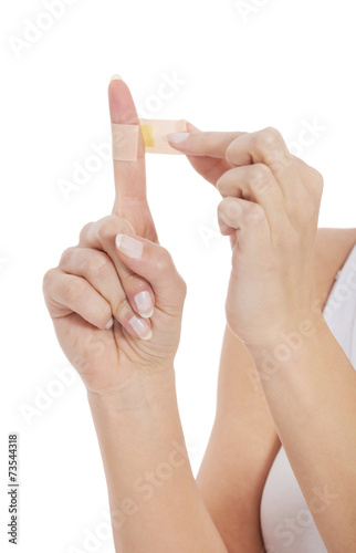 Close up of woman applying plaster on finger