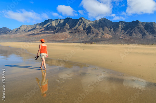 Young woman tourist walking on Cofete beach Fuerteventura island