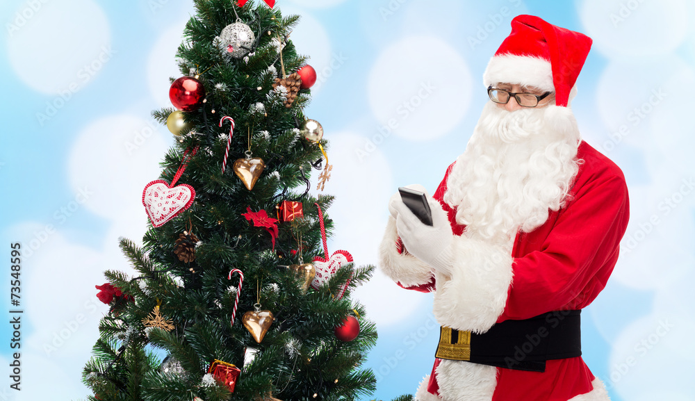 santa claus with smartphone and christmas tree santa claus with smartphone and christmas tree