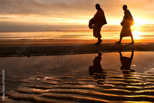 Silhouettes of monks on Hua Hin beach Thailand