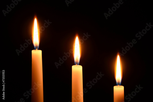 Three white candles on a black background