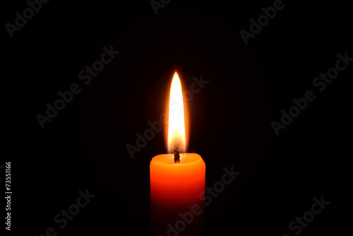 Orange candle burning on a black background
