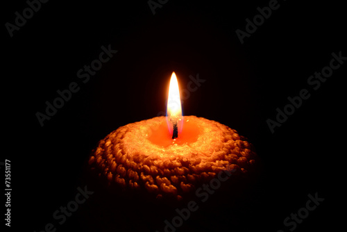 Yellow candle burning on a black background