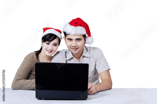 Couple with laptop and wearing christmas hat