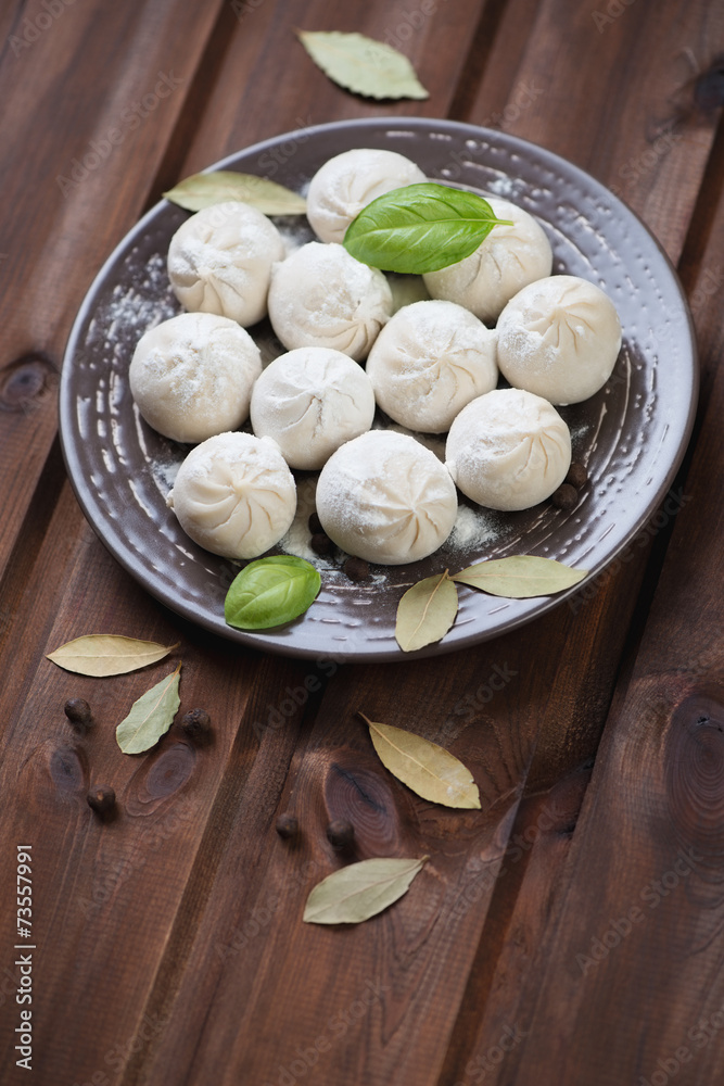 Ceramic plate with raw khinkali over rustic wooden background Ceramic plate with raw khinkali over rustic wooden background
