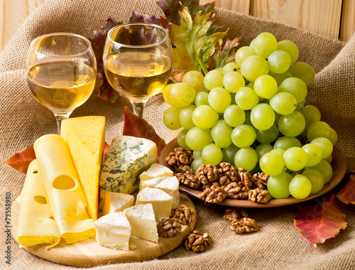 White wine with cheese, walnuts and grapes on sackcloth