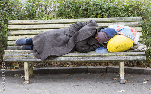 Homeless man sleeping on a bench photo