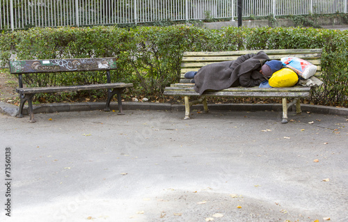 Homeless man sleeping on a bench photo