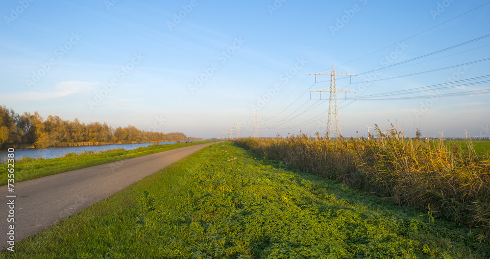 Fototapeta premium Road along a canal at sunset in autumn