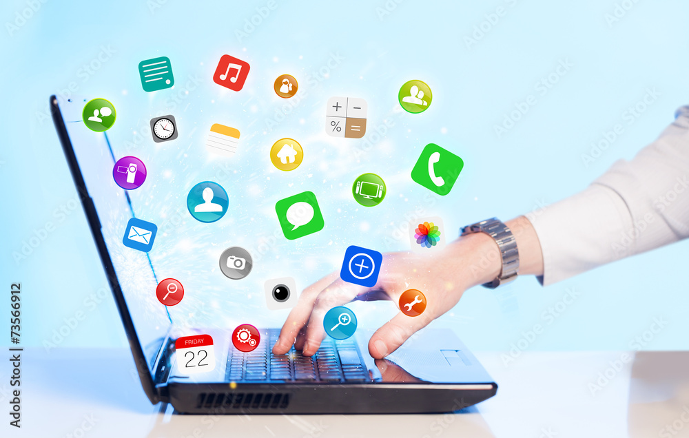 Hand pressing modern laptop with mobile app icons and symbols Hand pressing modern laptop with mobile app icons and symbols