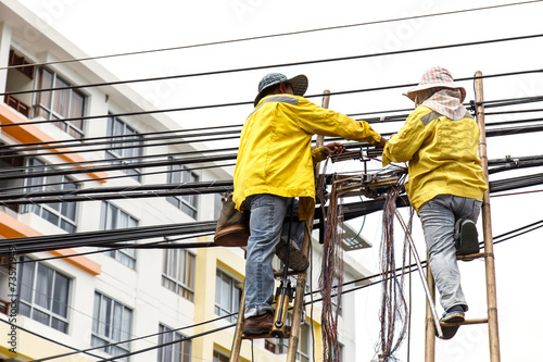worker on bamboo ladder is repairing telephone line © SKT Studio