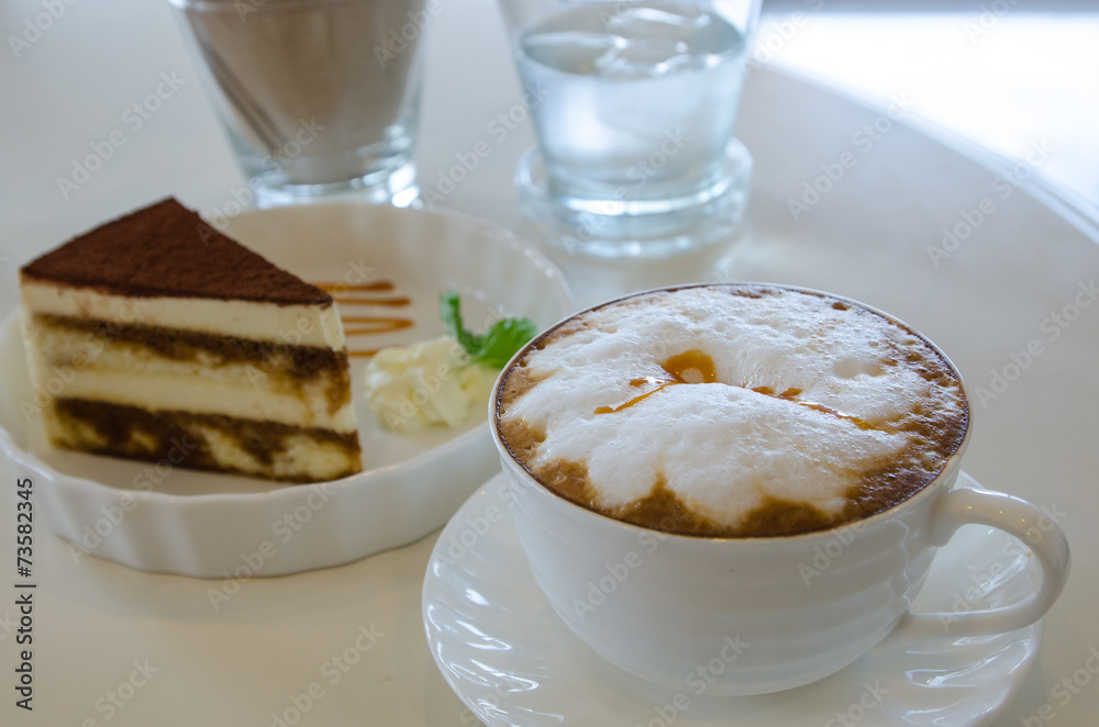 cup of cappuccino in a white cup with tiramisu cake on table cup of cappuccino in a white cup with tiramisu cake on table