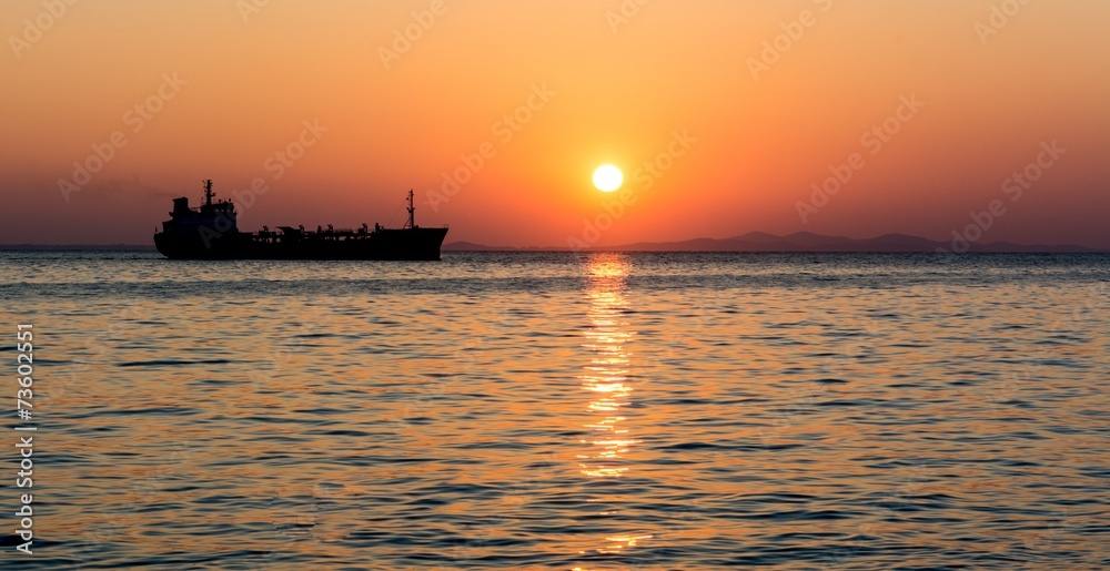 Silhouette of the cargo ship over the sunset