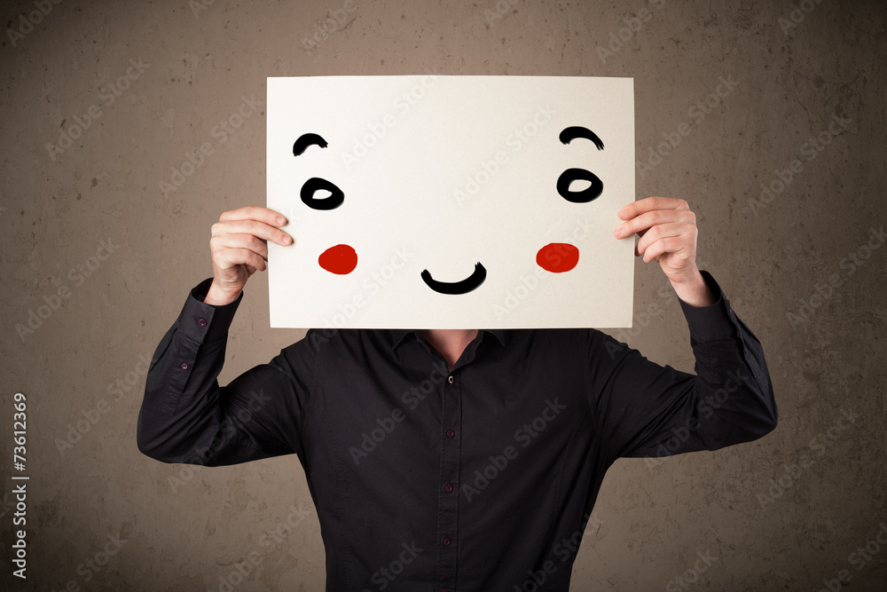 Businessman holding a cardboard with a smiley face on it Businessman holding a cardboard with a smiley face on it