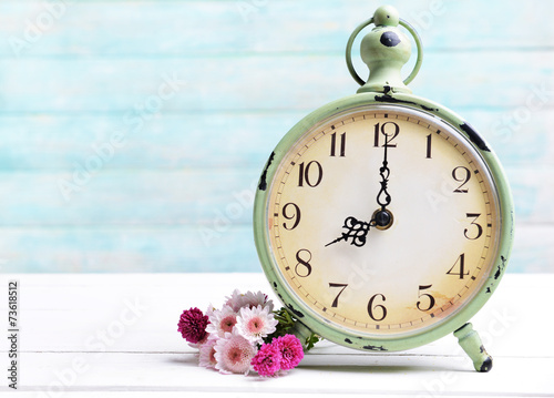 Fototapeta Naklejka Na Ścianę i Meble -  Beautiful flowers with clock on table on light blue background