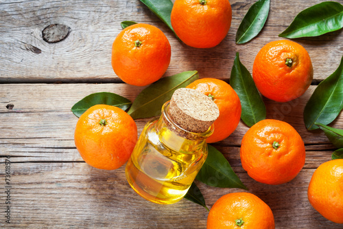Tangerines with leaves and bottle of essential citrus oil on a w