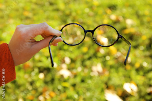 Glasses in hand on green grass background