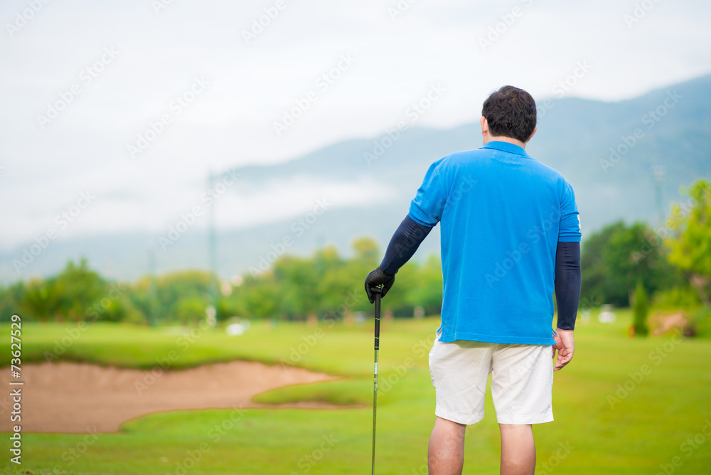 Golfer hits an fairway shot towards the club house Golfer hits an fairway shot towards the club house
