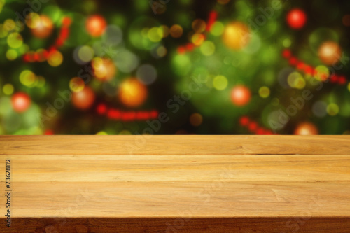 Empty wooden deck table over Christmas tree bokeh background