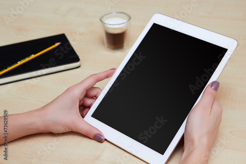 Woman hands holding white tablet in portrait mode, blank screen