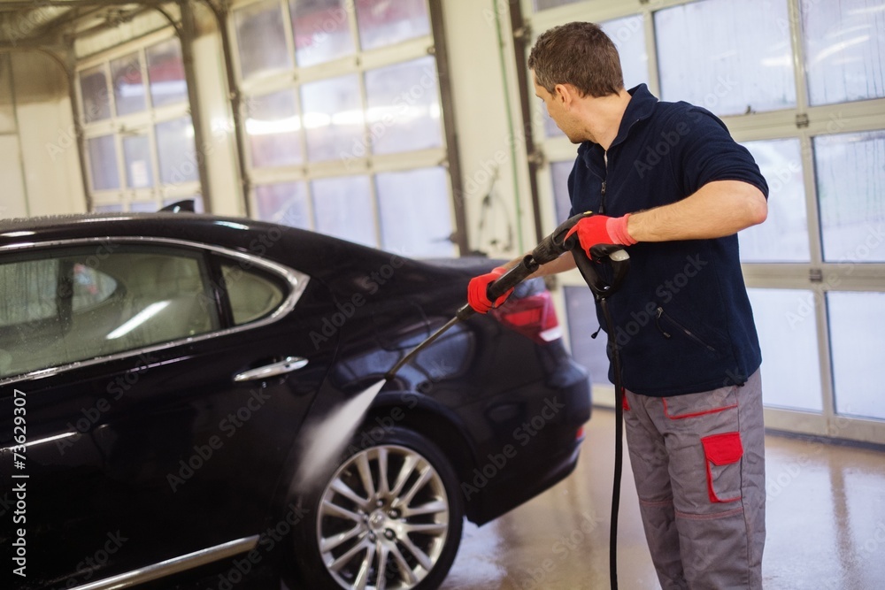 Man worker washing luxury car on a car wash Man worker washing luxury car on a car wash