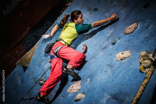 Young woman practicing rock-climbing on a rock wall indoors