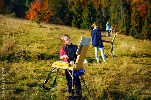 Young painters at work near waterfall