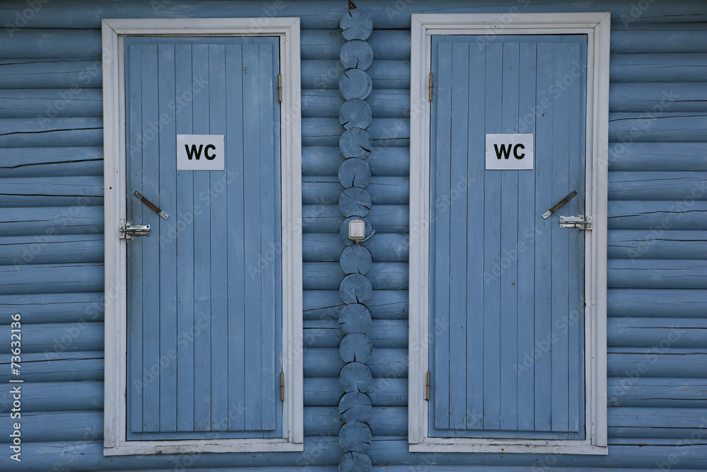 Fototapeta premium Toiletteneingangstüren im blauen Blockhaus